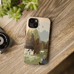 a phone case sitting on top of a wooden table next to a camera and plant