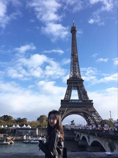 a woman is standing in front of the eiffel tower with her cell phone