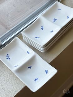 blue and white plates stacked on top of each other in front of a window sill