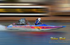 a man driving a speed boat in the water with his engine on it's side