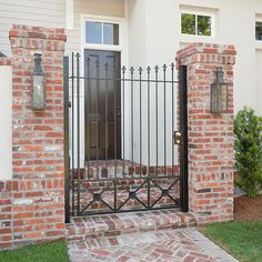 an iron gate in front of a brick house