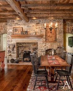 a rustic dining room with stone fireplace and wood table set for four, surrounded by antique rugs