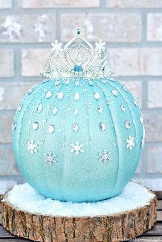 a blue pumpkin sitting on top of a piece of wood next to a brick wall