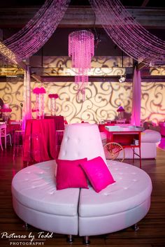 a pink and white couch sitting in front of a table with two red pillows on it