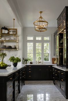 a large kitchen with marble counter tops and black cabinets, along with gold trimmings