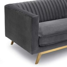 a grey velvet couch with wooden legs and armrests on an isolated white background