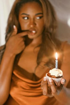 a woman holding a cupcake with a candle in it