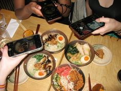 several people sitting at a table with plates of food and cell phones in front of them