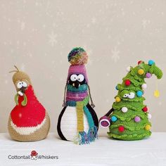 three crocheted christmas trees and two stuffed animals are on a table with snowflakes