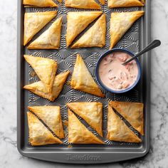 some food is laying out on a tray with dipping sauce in a small blue bowl