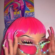 a woman with bright pink hair and eyeliners holding her hands up to her face