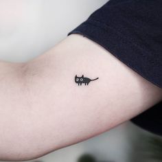 a small black cat tattoo on the arm