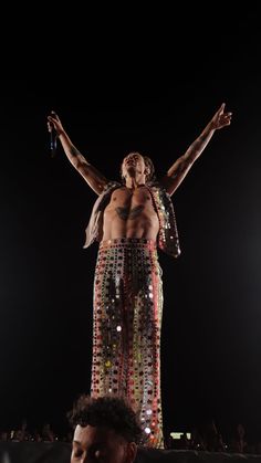 a man standing on top of a stage with his hands in the air