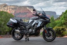 the motorcycle is parked on the side of the road with mountains in the back ground