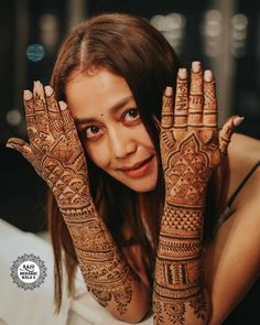 a woman holding her hands up with henna tattoos on it's arms and chest