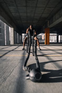 two people doing push ups on ropes in an empty parking garage with buildings in the background