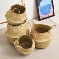 three woven baskets sitting on the floor next to a painting