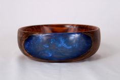 a blue and brown wooden bowl sitting on top of a white table