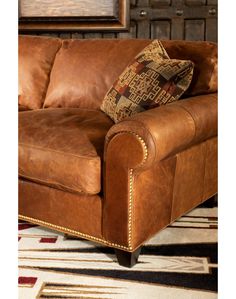 a brown leather couch sitting on top of a rug next to a wooden frame wall