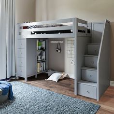 there is a loft bed with stairs in the room and a blue rug on the floor