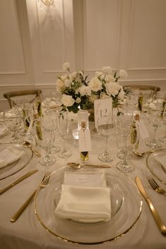 the table is set with white flowers and place settings