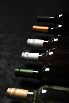 several bottles of wine are lined up in a row on a black tablecloth surface