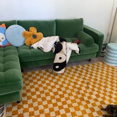 a green couch sitting on top of a checkered floor next to a black and white cat