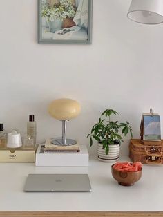 a white desk topped with a laptop computer sitting on top of a table next to a potted plant