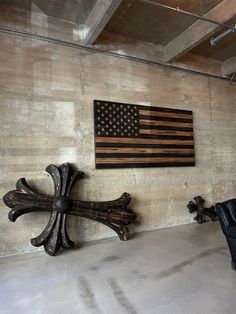 an american flag is hanging on the wall next to two wooden crosses in a room