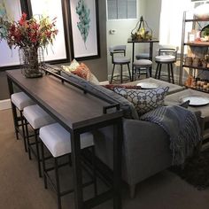 a living room filled with lots of furniture next to a dining table and bar stools