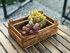 a wooden crate filled with grapes on top of a table