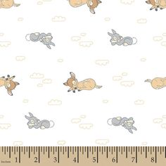 a ruler is next to a white fabric with cartoon animals on it and clouds in the background