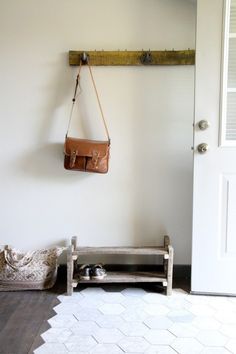 a purse hanging on the wall next to a white door with a wooden bench in front of it