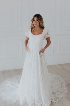 a woman in a white wedding dress standing on the floor with her hands on her hips