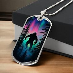 a dog tag with the image of a bigfoot on it and aurora lights in the background