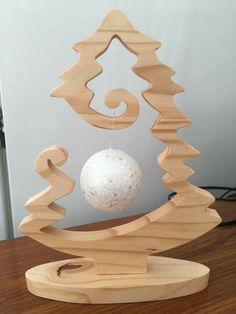 an ornament made out of wood with a white ball hanging from the top