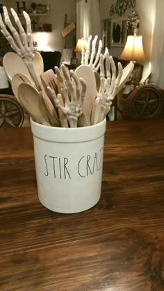 a white bucket filled with wooden utensils on top of a table