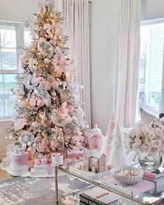 a decorated christmas tree in a living room with pink and silver decorations on the top