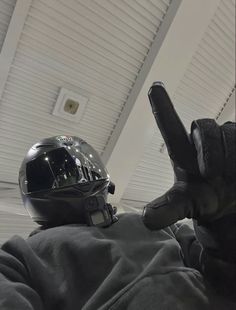 a person wearing a motorcycle helmet and holding their hand up in the air while sitting down