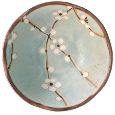 a blue plate with white flowers and branches on the inside is shown against a white background