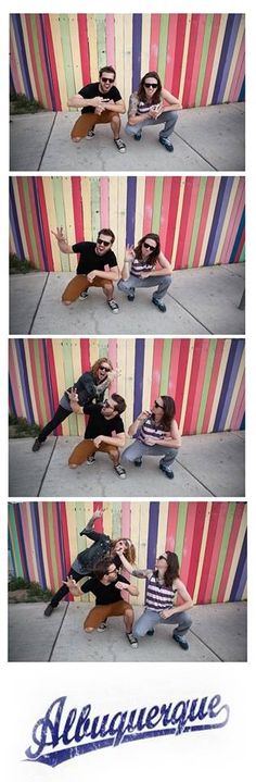 two people sitting on the ground in front of a colorful wall with words above them