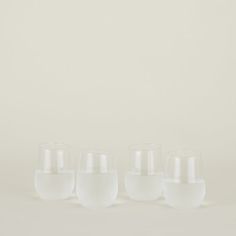 five glasses sitting next to each other in front of a white wall with no one on it