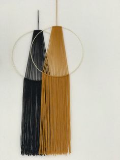 two black and gold tassels hanging on a white wall next to each other