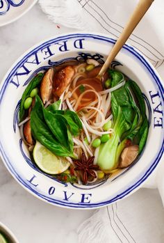 a white and blue bowl filled with soup next to chopsticks on a table