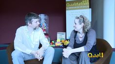 a man and woman sitting on a chair talking to each other in front of a poster