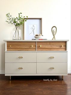 a white dresser with two vases on top of it next to a wooden floor