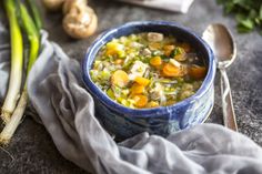 a bowl of soup with carrots and celery next to it on a table