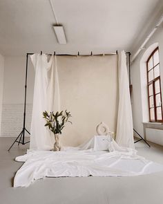 a white bed sitting under a window next to a vase with flowers on top of it