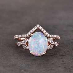 a white opal and diamond ring on a black surface with the center stone surrounded by diamonds