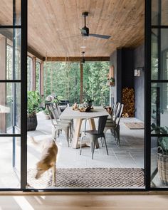 an outdoor dining area with wooden ceiling and glass doors that lead to the outside patio